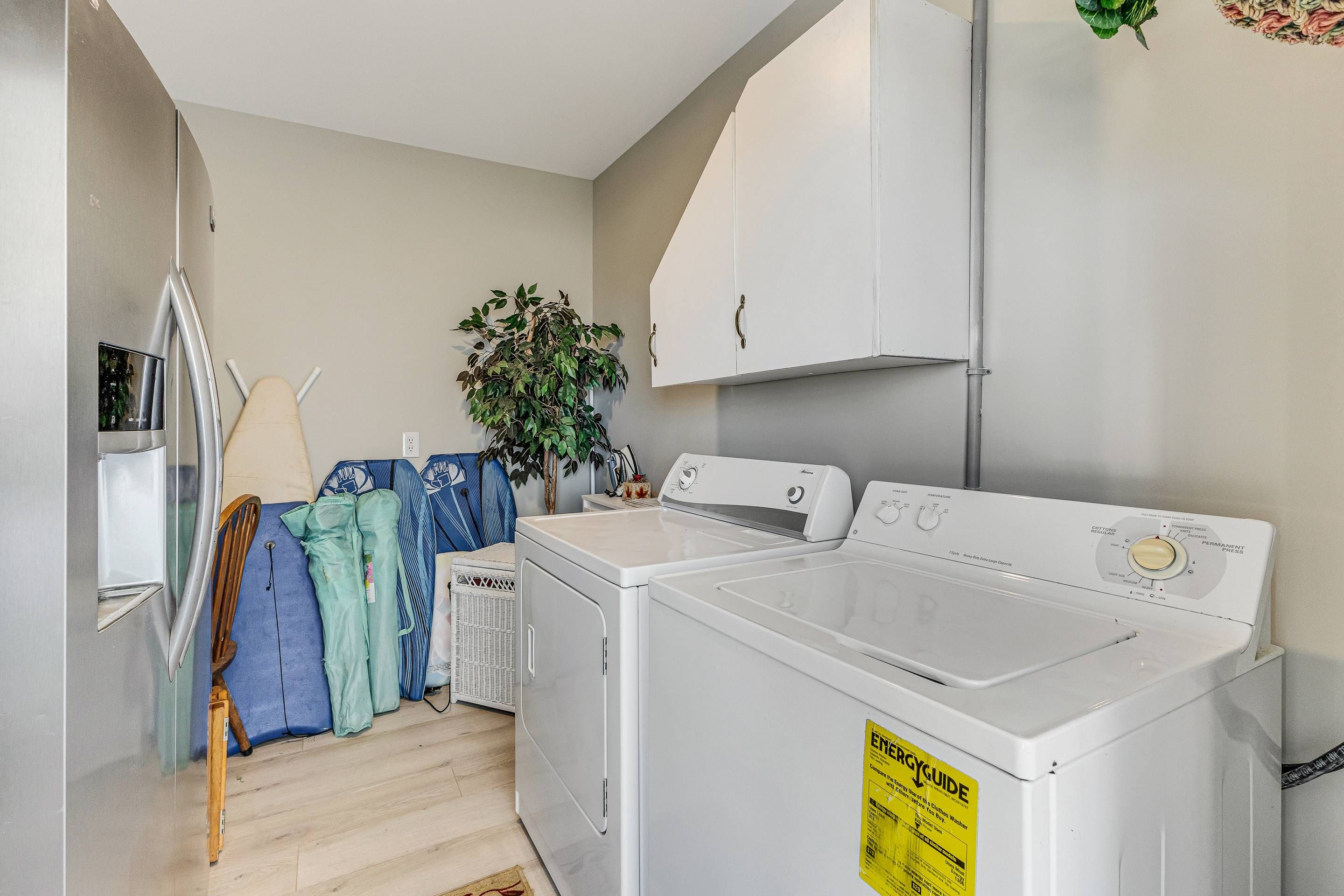 A laundry room with a washer and dryer, a drying rack, and a plant.