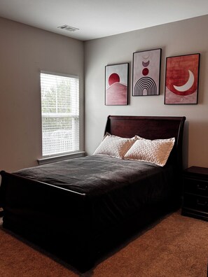 A bedroom with a bed, a window with blinds, and three wall-mounted artworks. - Spacious 5-bedroom, 8-bed house in welcoming Grovetown, w/ Rogue fitness room (Grovetown)