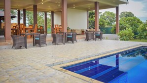 Ein Poolbereich mit gefliestem Boden, Liegestühlen und einem Pool.