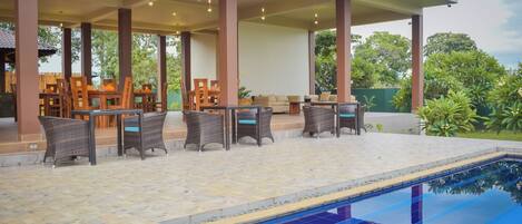 A poolside area with a tiled floor, lounge chairs, and a pool.