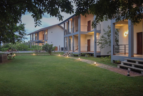 A modern multi-story building with a well-maintained lawn and outdoor seating area. - Hotel Sigiriyaaya - Jetwing Select (Sigiriya)