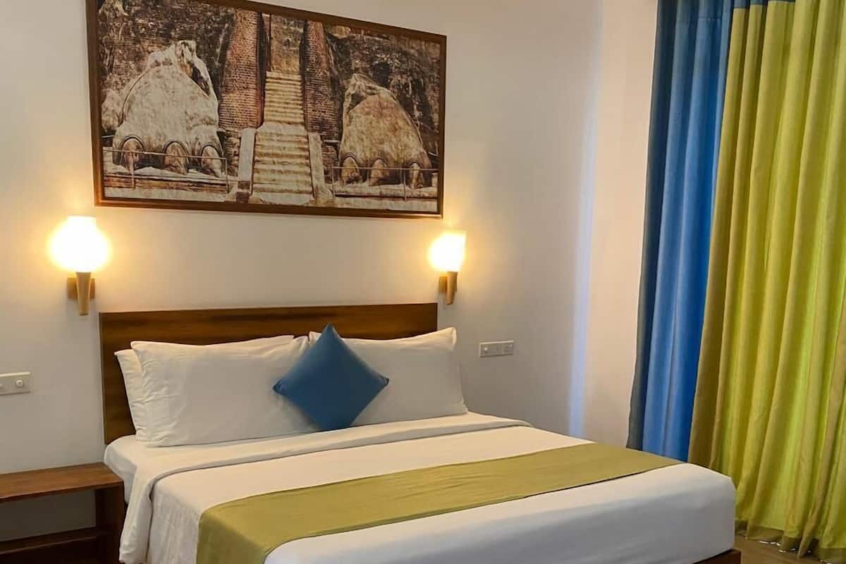 Uma cama bem arrumada com cabeceira de madeira, duas luminárias laterais e um quadro acima.