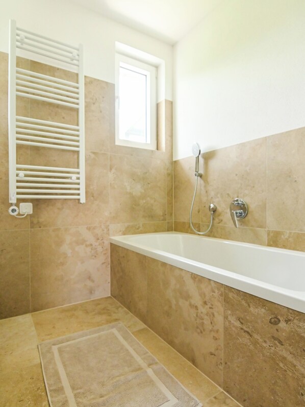 Un baño con bañera, ducha y perchero.