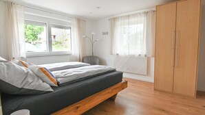 Ein Schlafzimmer mit einem Bett, einem Holzschrank und einem Fenster mit Vorhängen.
