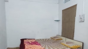 Een kamer met een bed, een plafondventilator en een raam met gordijn.