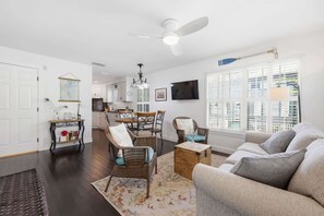 Un salon comprenant un canapé, des fauteuils, une table basse, un téléviseur et un coin repas avec des chaises et une table.