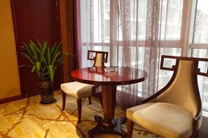 A round table with four chairs, a potted plant, and a view through a window with curtains. - Siji Xiaozhu Hotel (Danzhai)