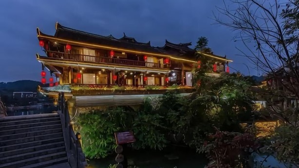 A traditional building with a balcony, steps leading to it, and a small garden area. - Siji Xiaozhu Hotel (Danzhai)