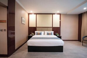 A hotel room with a large bed, a headboard with built-in lighting, a nightstand with a lamp, and a chair. - Siji Xiaozhu Hotel (Danzhai)