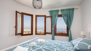 Un dormitorio con cama, dos ventanas, vistas de la ciudad y una lámpara en el techo.