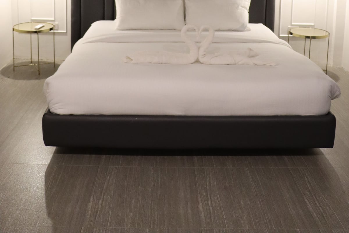 A modern hotel room with a large bed, dark headboard, and two bedside tables with lamps.