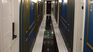 A hotel corridor with blue walls, gold trim, and white doors. - H Mansion Hotel (Tandag)