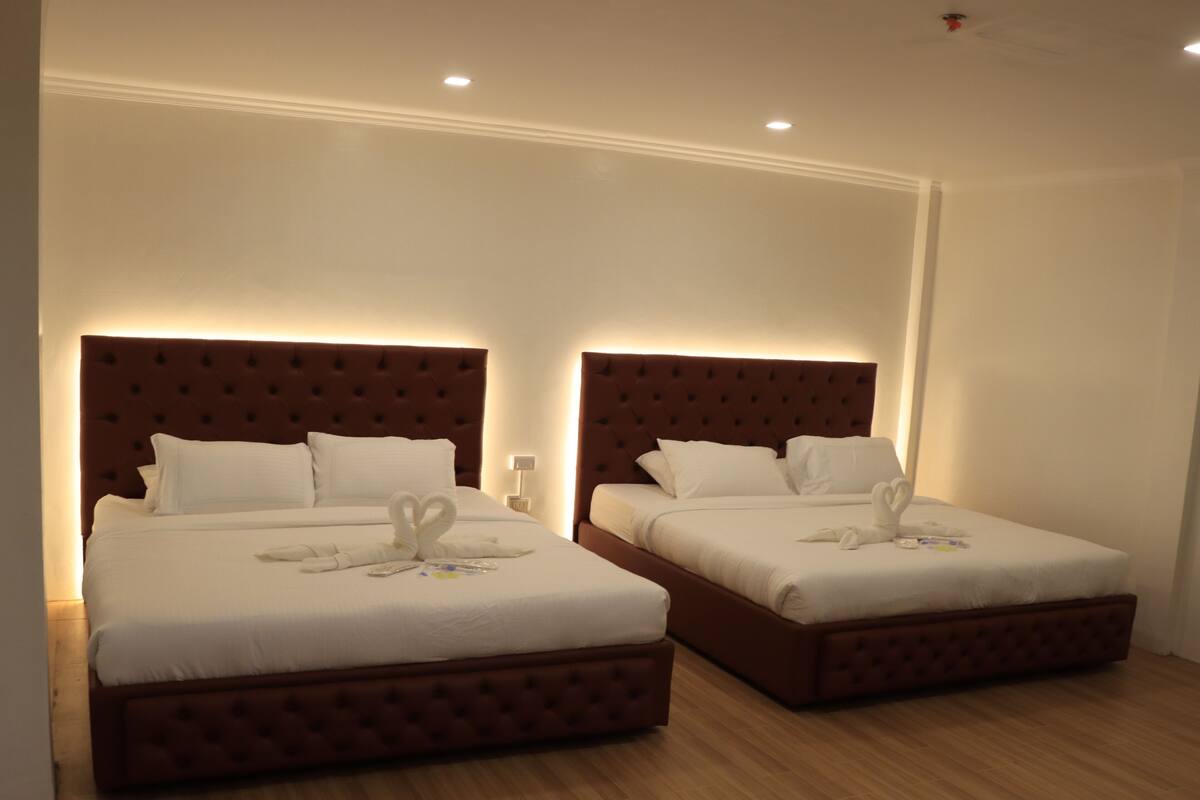 A hotel room with two beds, each with a brown headboard and white bedding.
