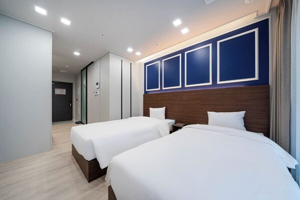 A hotel room with two beds, a wooden headboard, and a white wall with framed panels.