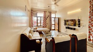Una sala de estar con sofá, sillones, una mesa de centro, televisor y ventilador de techo.
