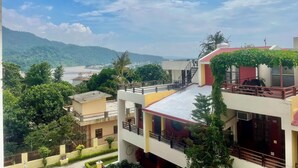Un edificio de varios pisos con balcones, un río al fondo y un paisaje montañoso.