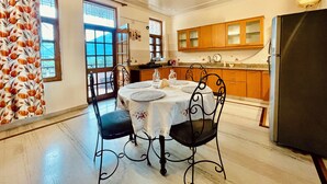 Un comedor con una mesa redonda, cuatro sillas y una cocina al fondo.
