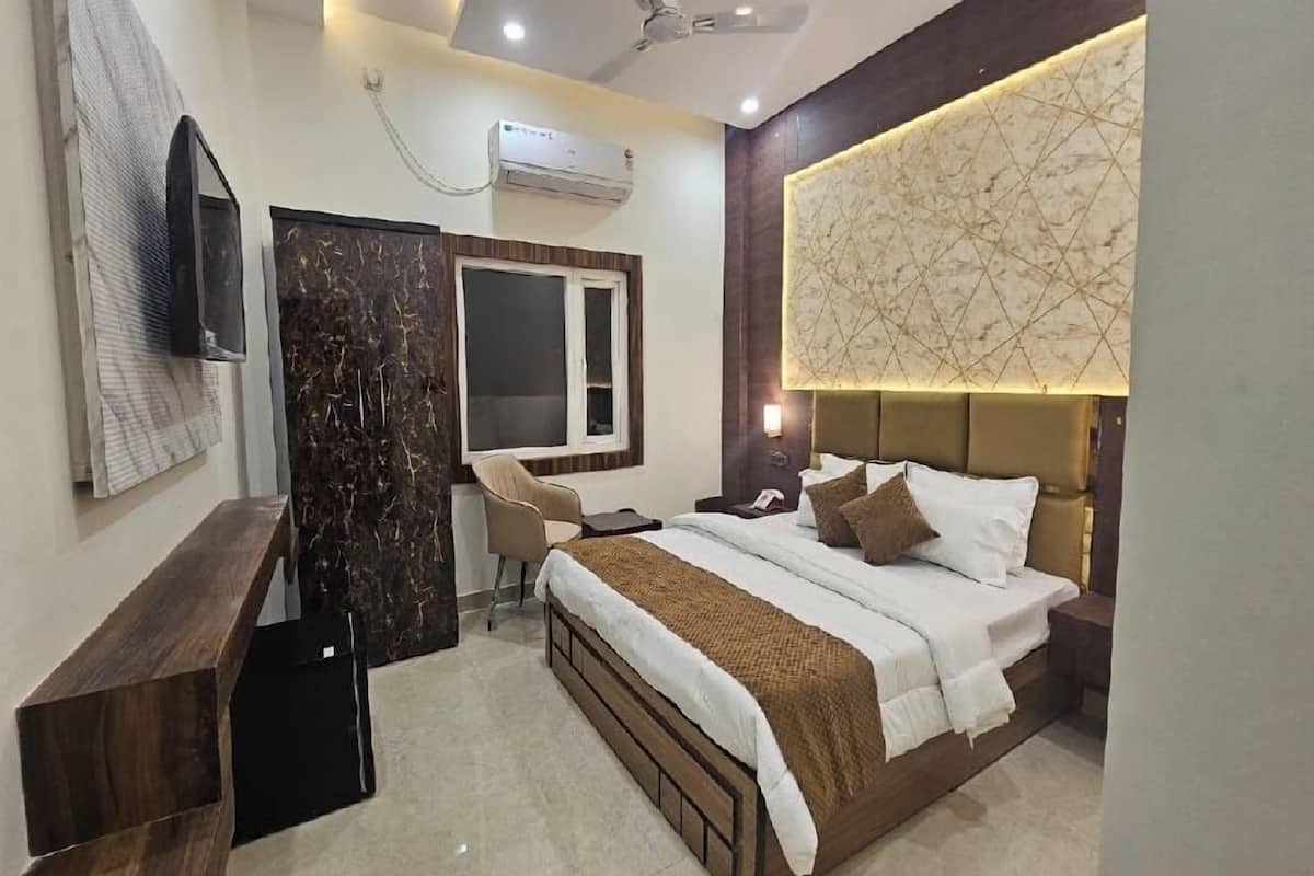 A modern hotel room with a bed, a desk, a chair, and a television.