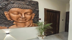 Un murale raffigurante una statua di Buddha in un corridoio, con una pianta in vaso sullo sfondo.