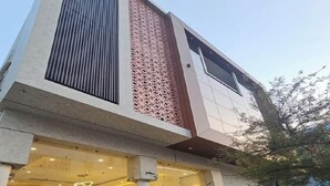 Un edificio moderno con un'ampia entrata in vetro, una facciata decorativa e un estintore ben visibile.