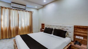 Een hotelkamer met een bed, nachtkastje, telefoon en een airconditioning.