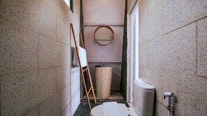 A narrow bathroom with a toilet, a wooden ladder, a round mirror, and a trash bin. - Luxcamp Dieng by Horison (Kejajar)
