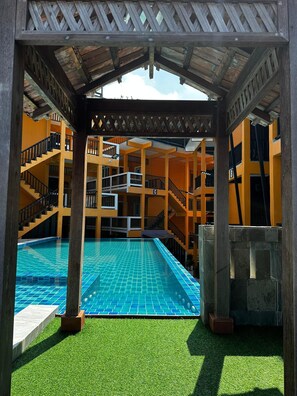Enjoy a refreshing swim in the pool surrounded by a deck and a wooden pergola.