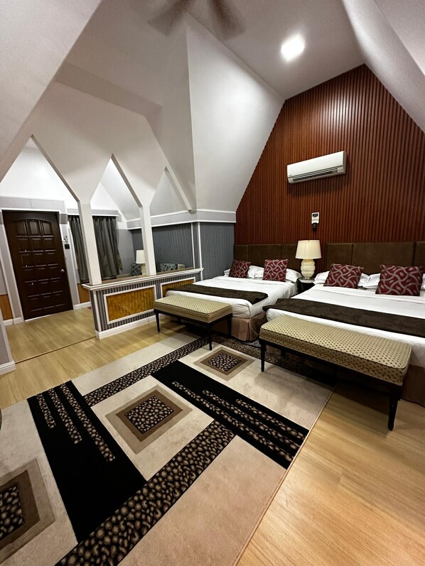Una habitación de hotel moderna con dos camas, techo inclinado de madera y un balcón.