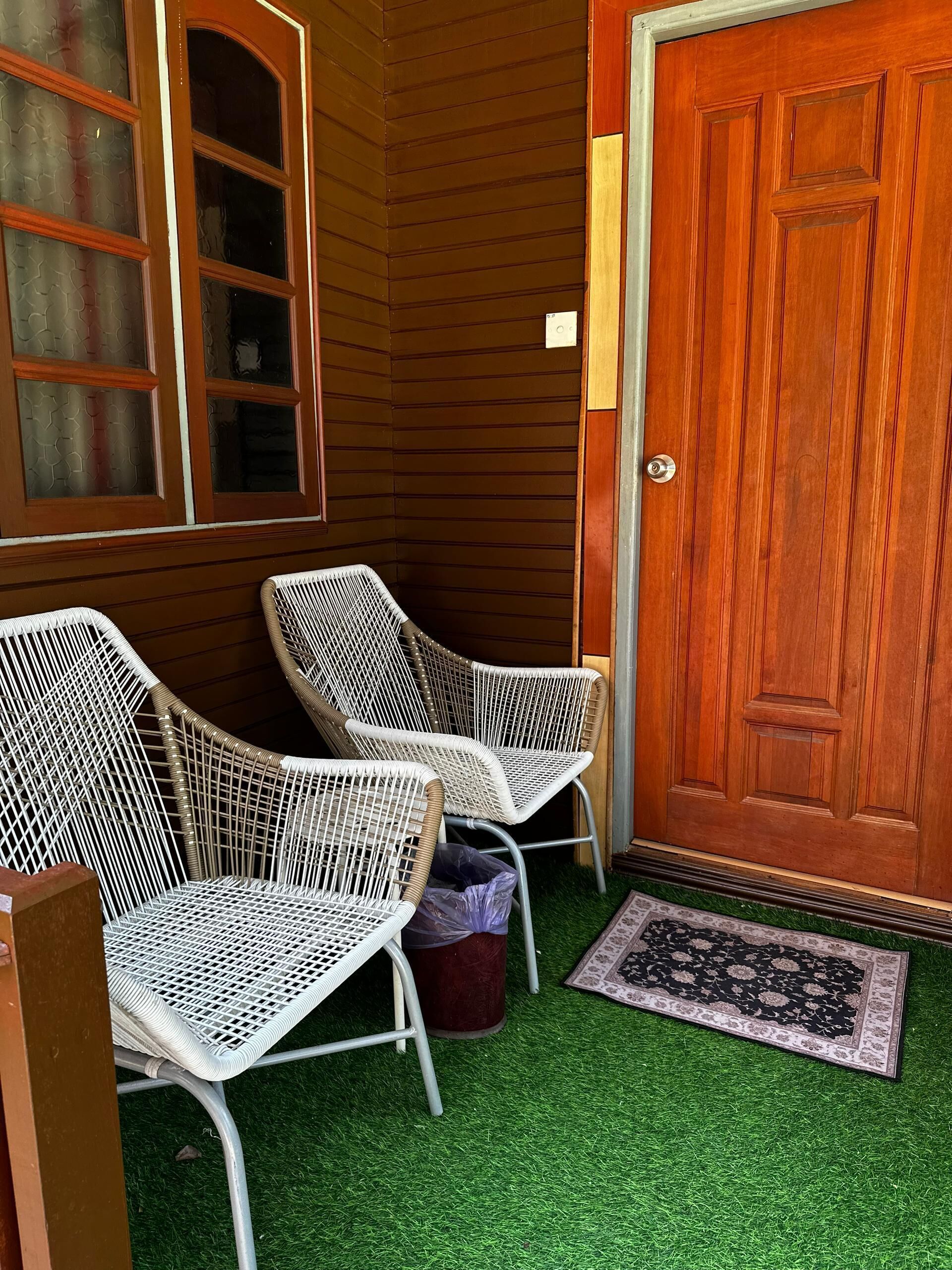 A corner of a room with two wicker chairs, a wooden door, and a window with frosted glass.