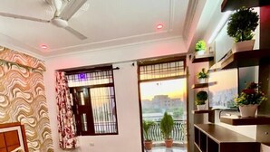 Un dormitorio con cama, ventilador de techo, ventana con vistas y balcón con plantas.