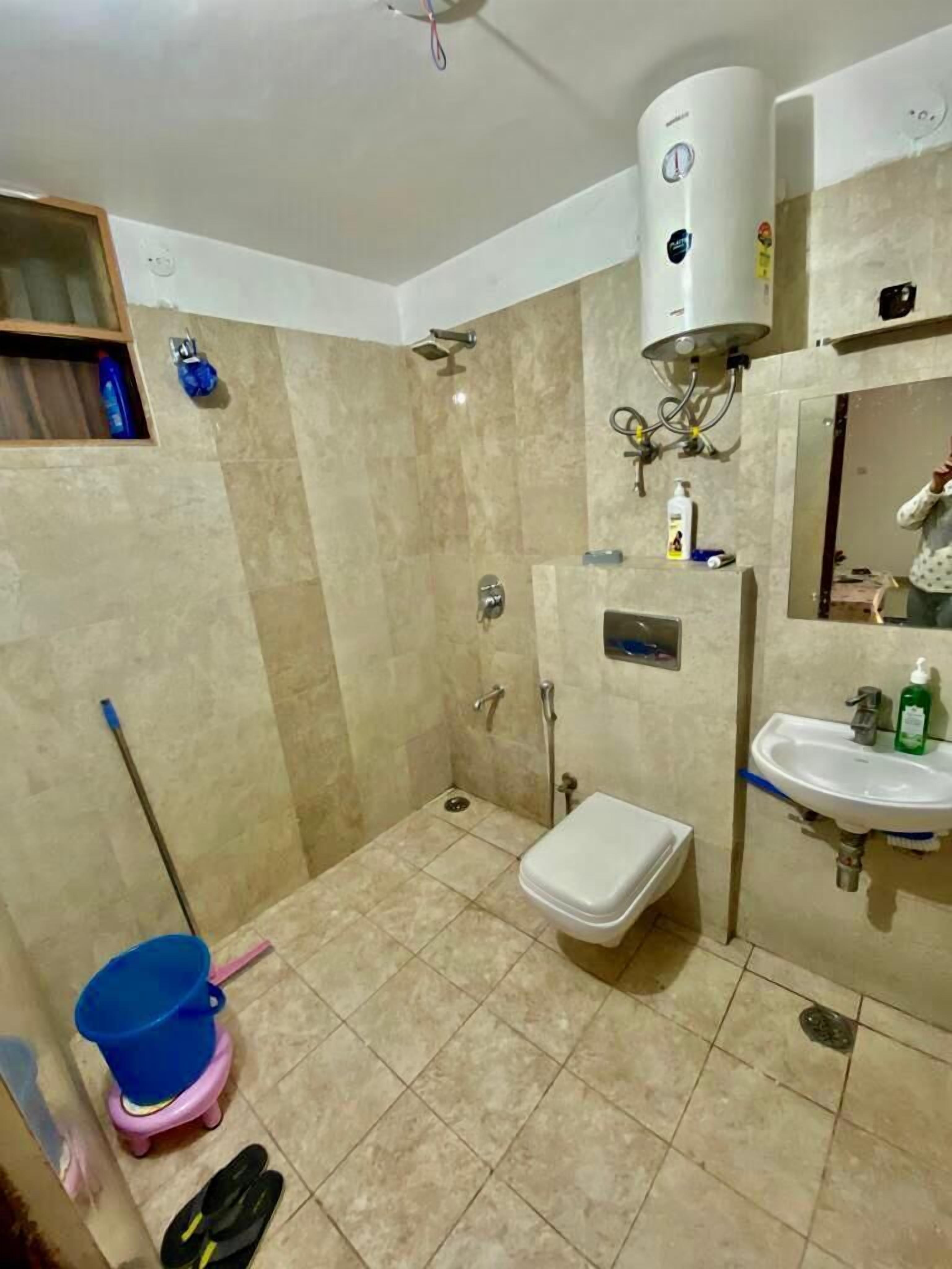 A bathroom with a shower, toilet, sink, and a water heater.