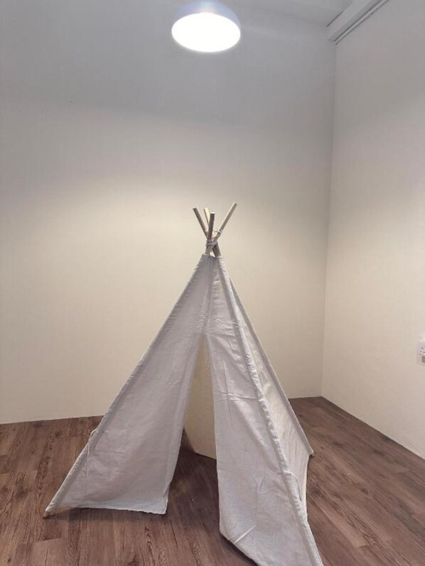 A room with a white teepee tent in the corner, wooden flooring, and a white wall. - Leo66 Guesthouse (Muar)