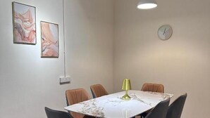 A dining area with a round table, six chairs, a wall clock, and two abstract paintings. - Leo66 Guesthouse  (Muar)