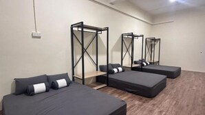 A room with four beds arranged in a row, each with a wooden floor and a white ceiling. - Leo66 Guesthouse  (Muar)