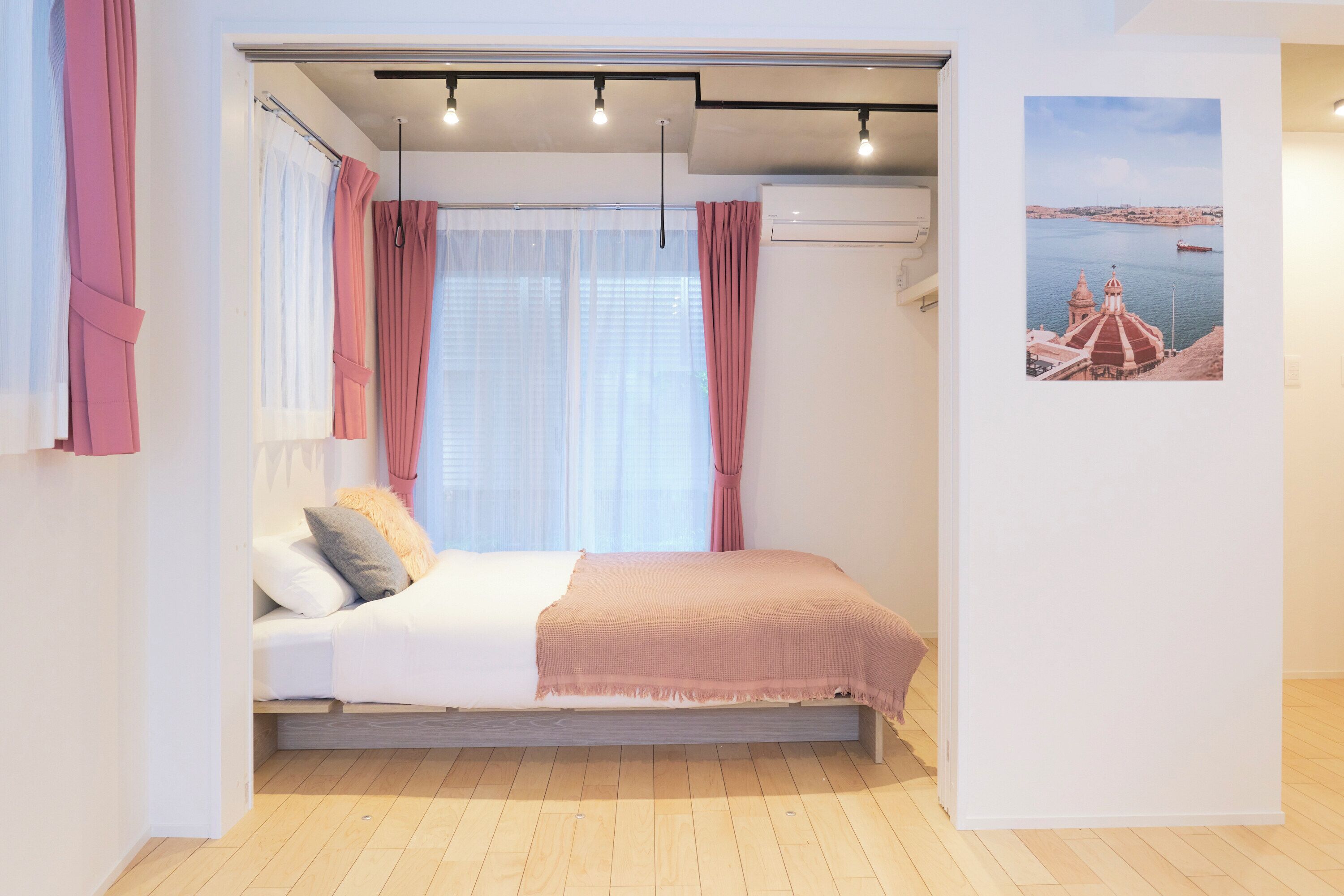A bedroom with a bed, curtains, a window, and a wall-mounted air conditioner.