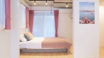 A bedroom with a bed, curtains, a window, and a wall-mounted air conditioner.