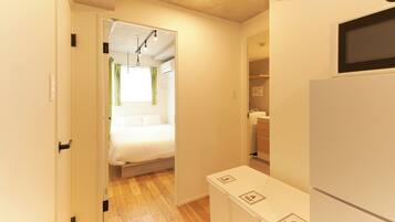 A narrow hallway with a bed, a white cabinet, and a microwave.