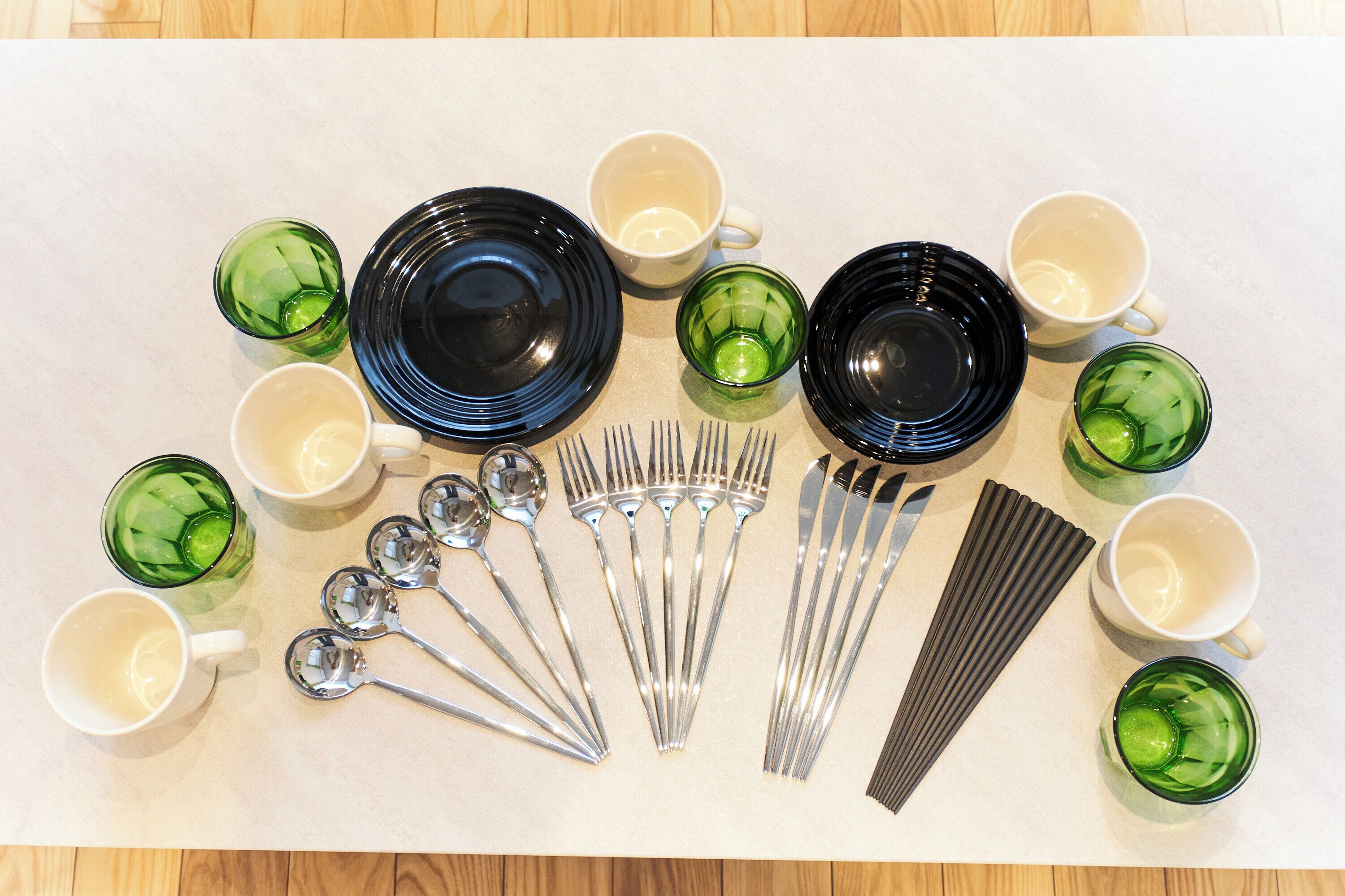 Une table dressée avec des assiettes, des bols, des tasses et des couverts.
