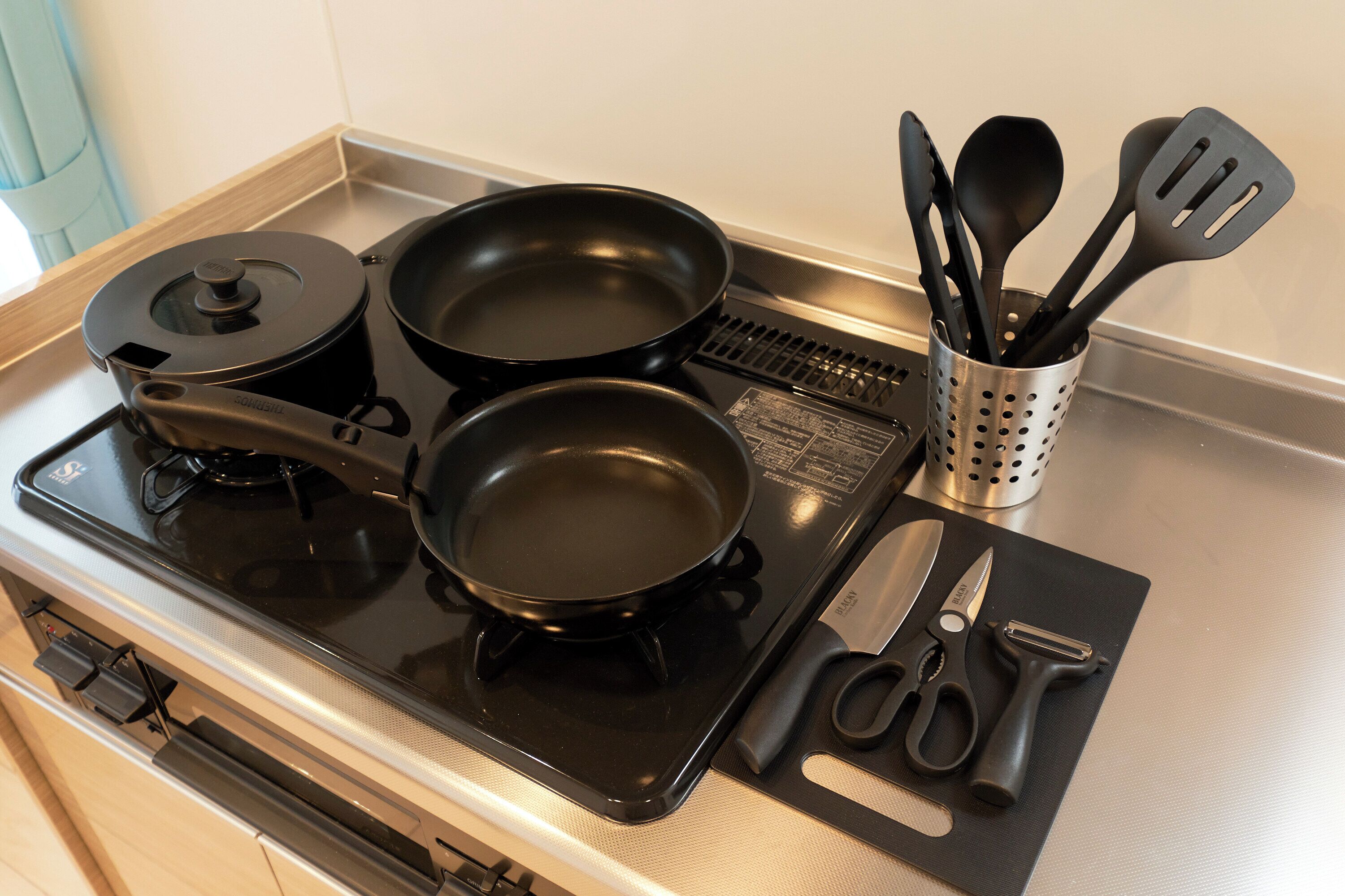 A kitchen with a stove, pots, a spatula holder, and a cutting board with utensils.