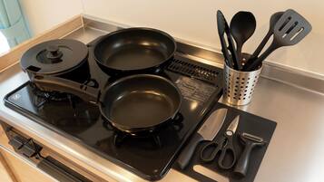 A kitchen with a stove, pots, a spatula holder, and a cutting board with utensils.