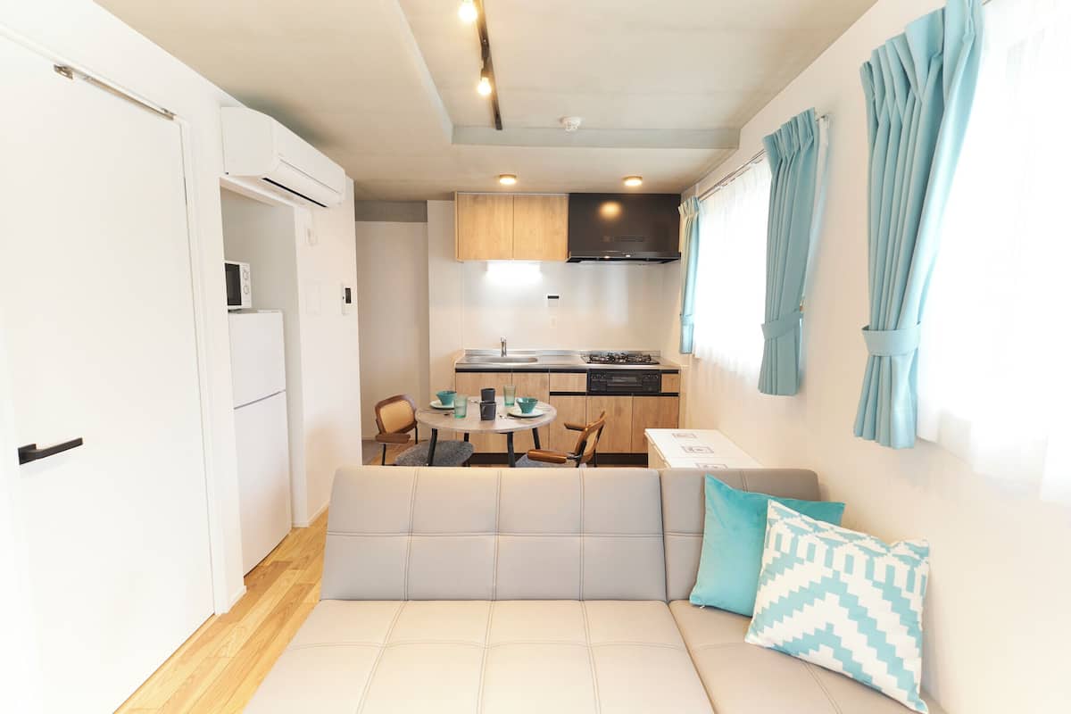 A compact living space with a kitchenette, a sofa with cushions, and a dining area.