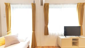 Una habitación con cama, televisión sobre un mueble y cortinas.