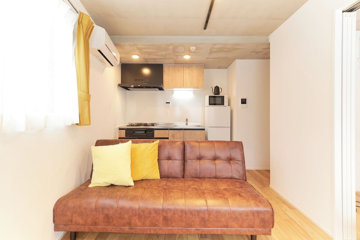 A compact living space with a sofa, a kitchen area, and a dining table.