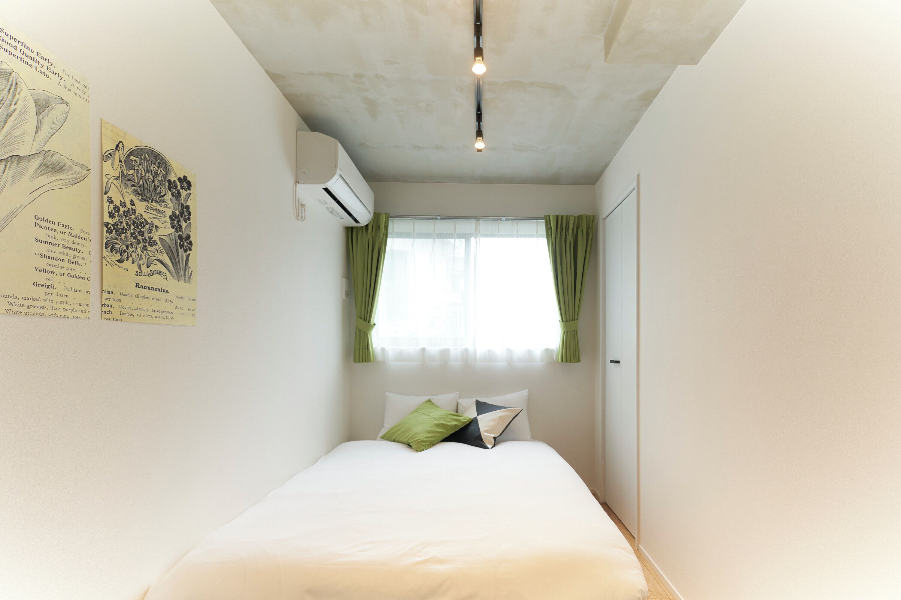 Een slaapkamer met een bed, groene gordijnen, een raam en wanddecoratie.