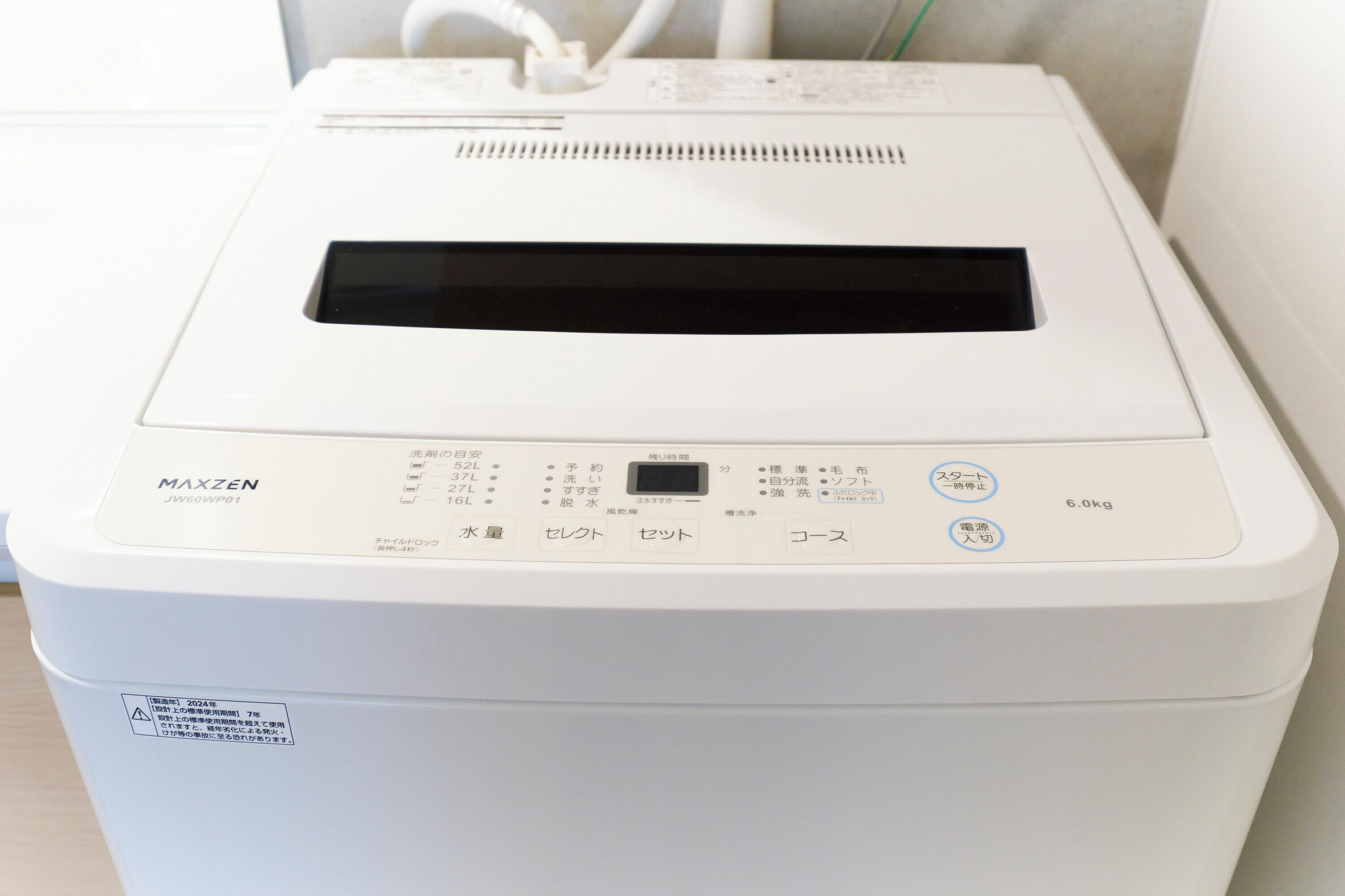 A white MAXZEN washing machine with a control panel, a digital display, and a label with Japanese text.