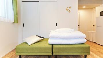 A room with two green ottomans, a white door, and a white wall with a gold decoration.