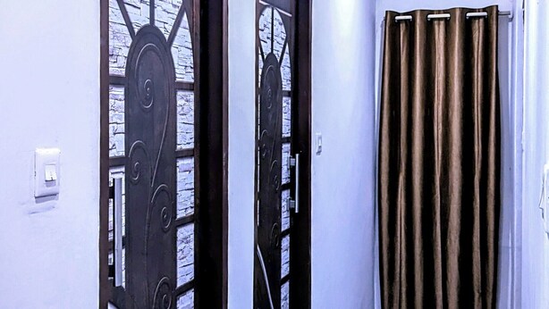 A hallway with two doors marked '407', a patterned floor, and a curtain at the end. - Hotel Jee (Varanasi)