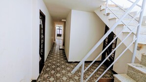 A narrow hallway with a tiled floor and a staircase with metal railings. - Hotel Jee (Varanasi)