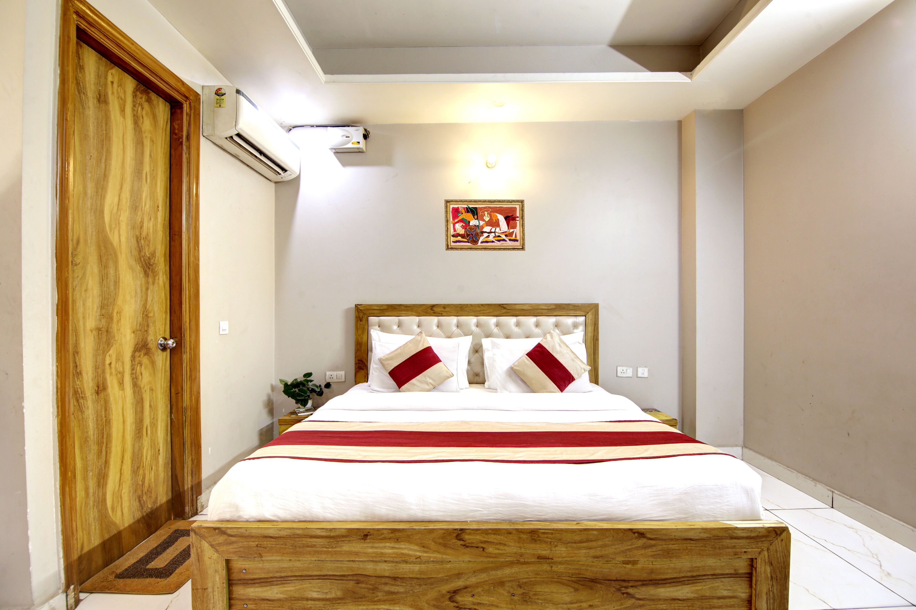 Un dormitorio con estructura de cama de madera, ropa de cama blanca y un corredor de cama a rayas rojas y blancas.