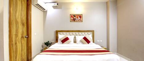 Un dormitorio con estructura de cama de madera, ropa de cama blanca y un corredor de cama a rayas rojas y blancas.